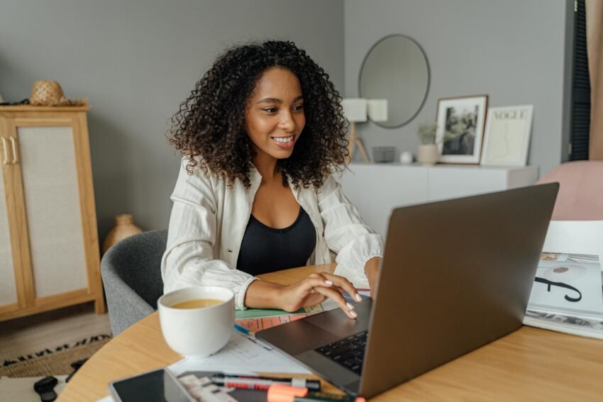 Woman in white blazer using macbook pro on brown wooden table